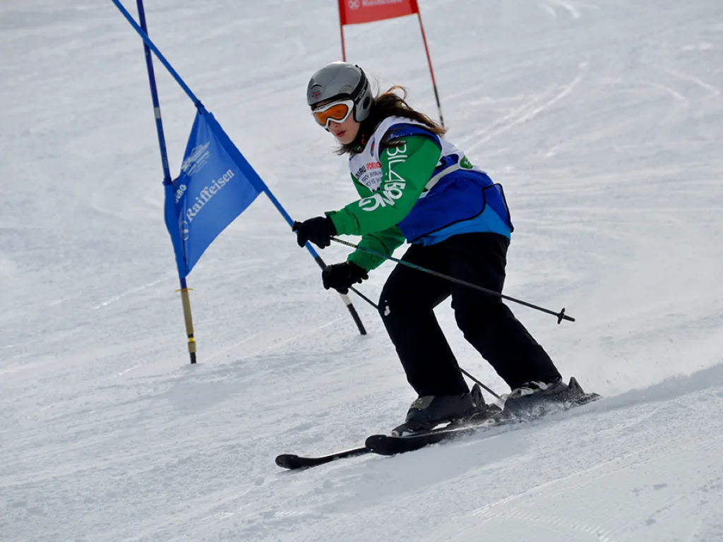 Skifahrerin in grüner Jacke zieht eine Kurve am Tor.